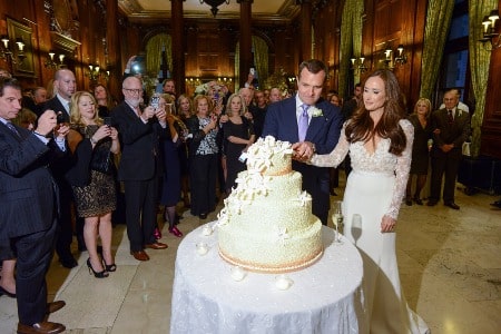 The duo is cutting a four layered cake.